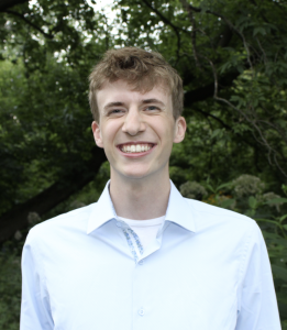 Headshot of a man in a button-up shirt smiling