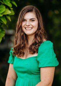 Headshot of a woman in a green dress smiling