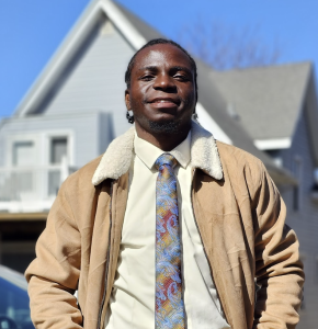 Photo of a man smiling with a tan jacket