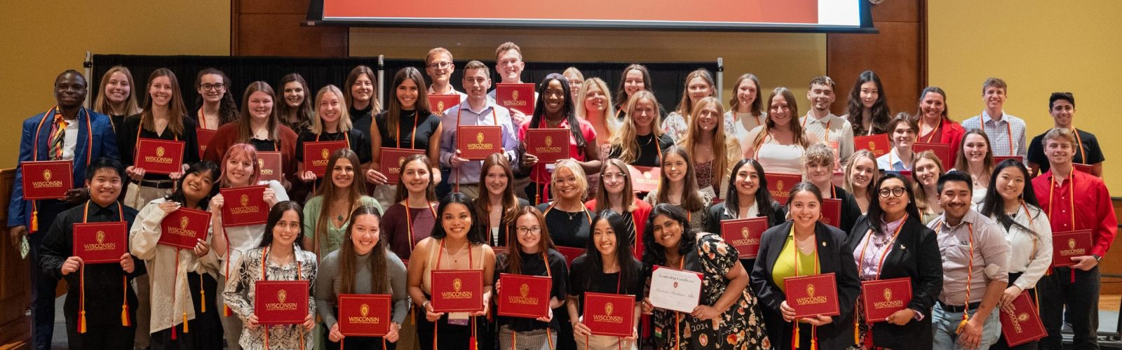 Group photo of leadership certificate recipients holding their red diploma covers.