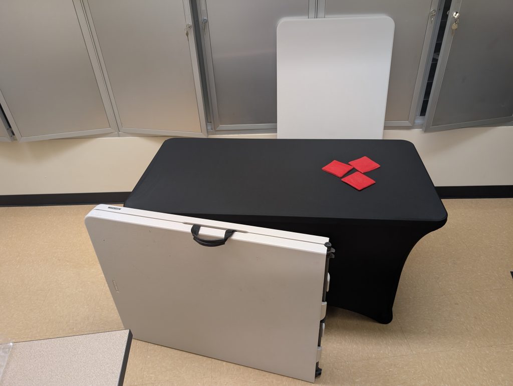 Three tables (one set up) with a table cloth and bean bag paper weights to show some of the PRC's offerings.