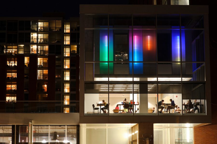Below the glow of colored lights, students are seen studying in a common area of 333 East Campus Mall