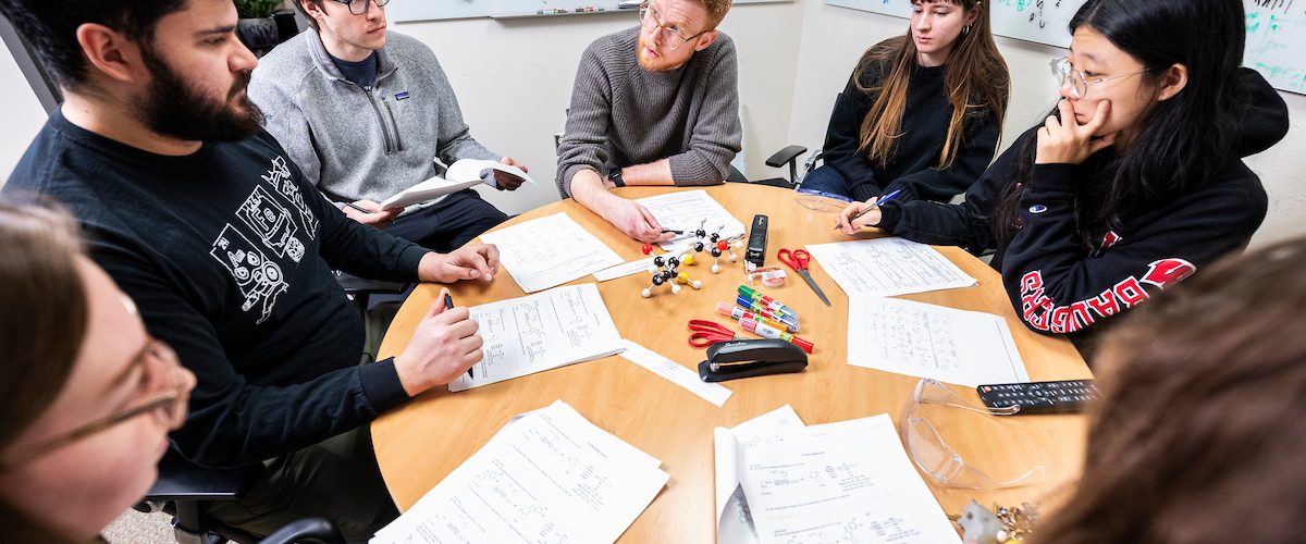 Zachary Wickens (at center wearing eyeglasses), associate professor of chemistry in the College of Letters & Science, holds a team meeting with undergraduate and graduate students working in his lab