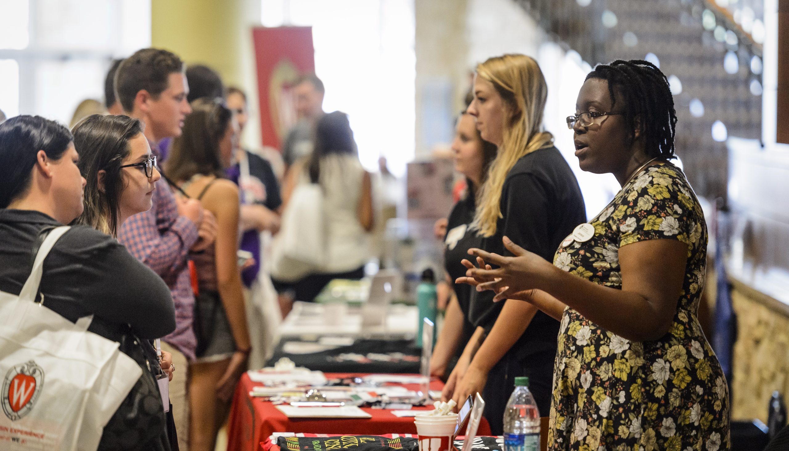 Students talks with a vendor while browsing their table at a tabling fair.