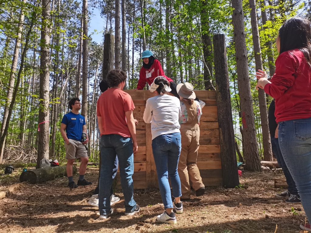 A group of students in the woods watching a live demonstration.