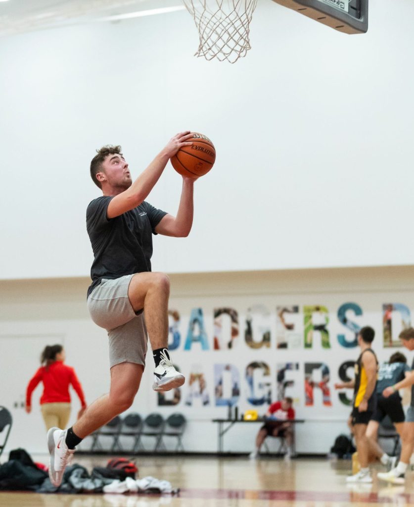 Student jumping high to reach the basketball net with the ball to score a point