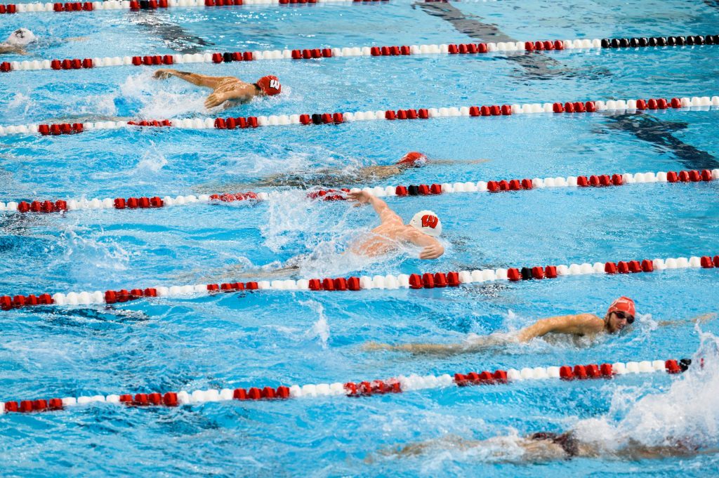 5 lanes of a swimming pool occupied with swimmers showcasing different strokes at the Nick