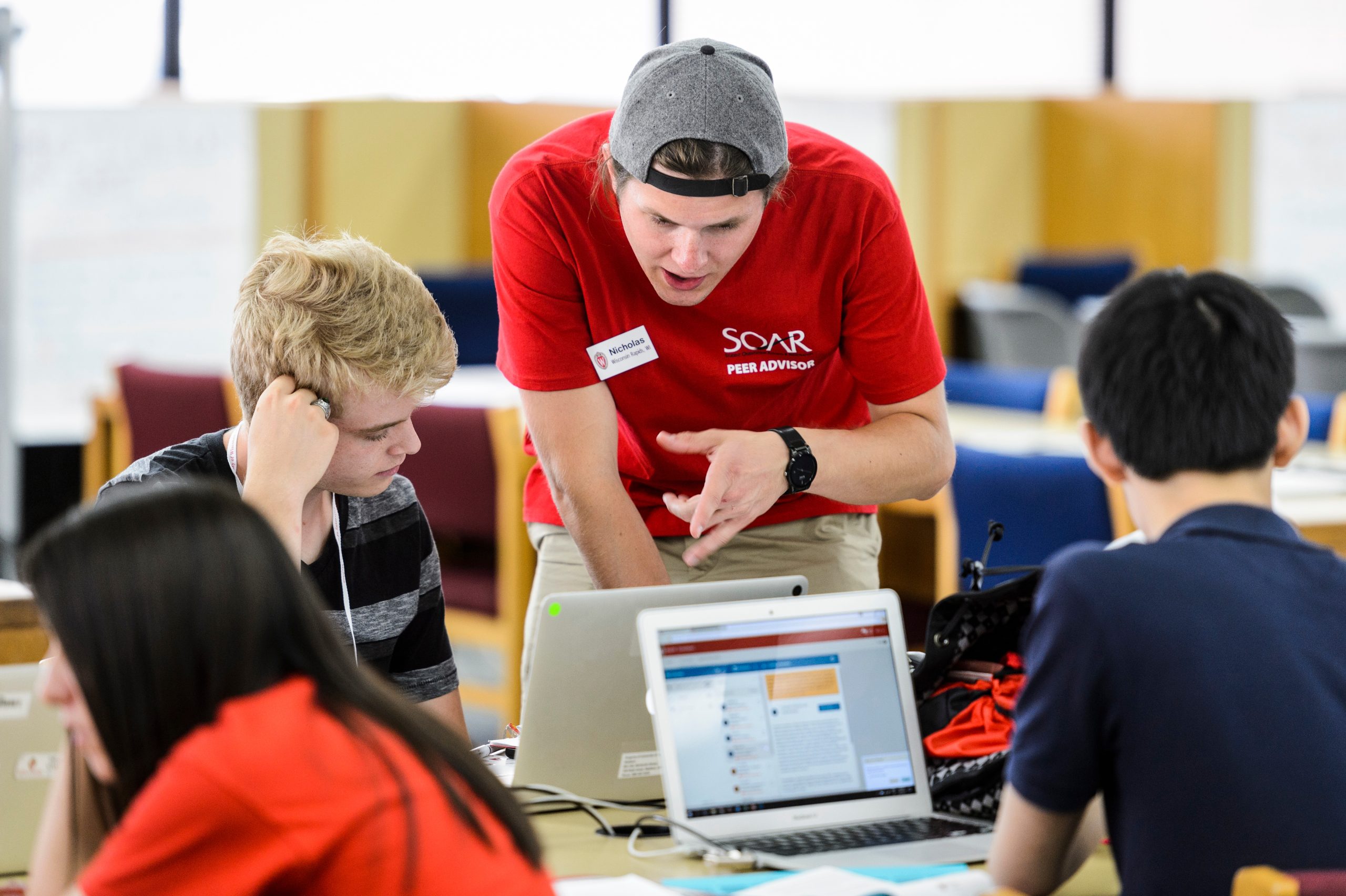 Standing, College of Engineering student-peer advisor works with incoming first-year undergraduate student, left, to register for his classes using a laptop computer during a Student Orientation, Advising and Registration (SOAR) session at College Library in Helen C. White Hall at the University of Wisconsin-Madison.