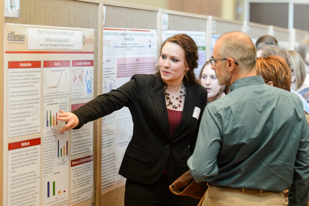 Student showing a poster to an audience at the Undergraduate Symposium.