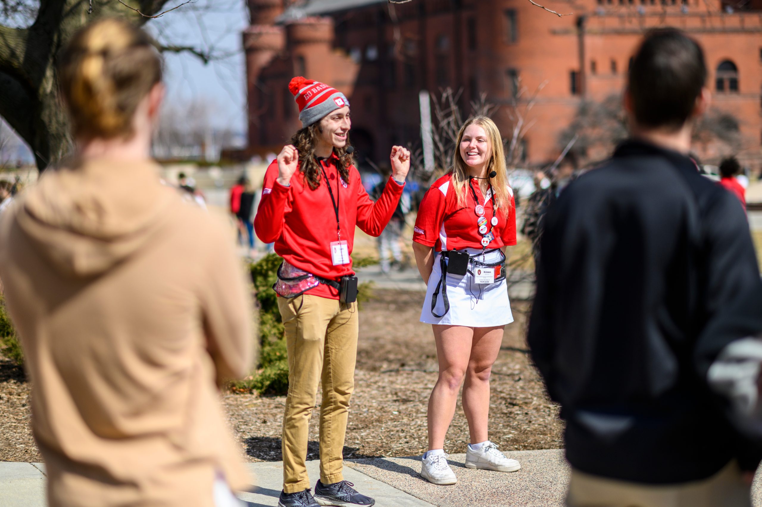 Two tour guides with Campus and Visitor Relations, talk to a group of prospective students and parents on a sunny spring day at the University of Wisconsin–Madison.