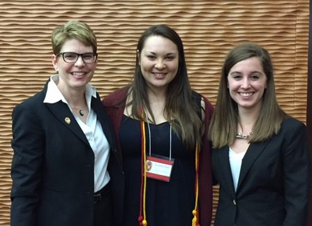 3 women, Anne Martino, Alexandria Pham, and Kayla Sippl, who were awarded the Leadership Awards pose in front of a brown textured background.