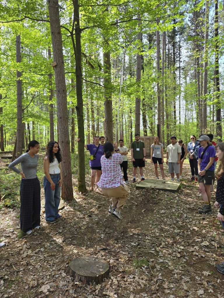 An outdoor shot of a group of 2025 WEBT students participate in a challenge course activity at the Central Wisconsin Environmental Station.