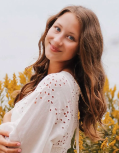 A woman in a white dress smiling.
