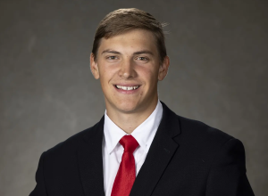 A man wearing a red tie, smiling.