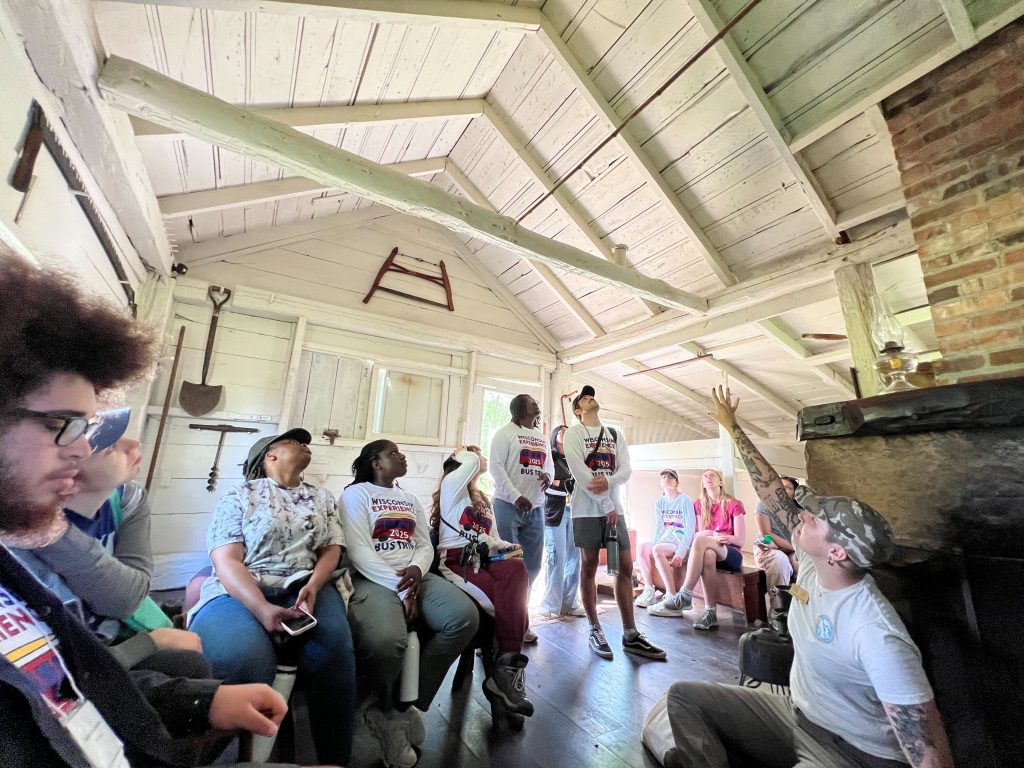 A group of 2025 WEBT students look up at the white rafters and vaulted ceiling of Aldo Leopold's family house/shed during a tour of the Aldo Leopold Foundation.