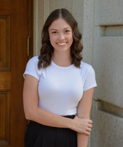 A woman smiles while wearing a white shirt.