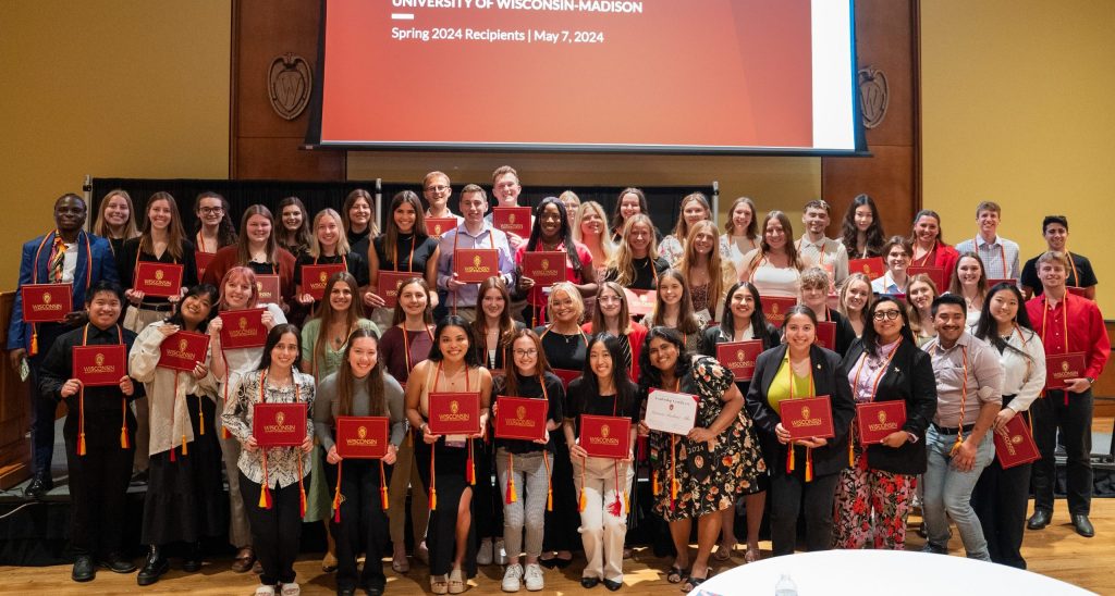 Group photo of leadership certificate recipients holding their red diploma covers.