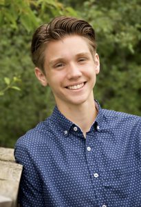 A man in a blue button up shirt smiling