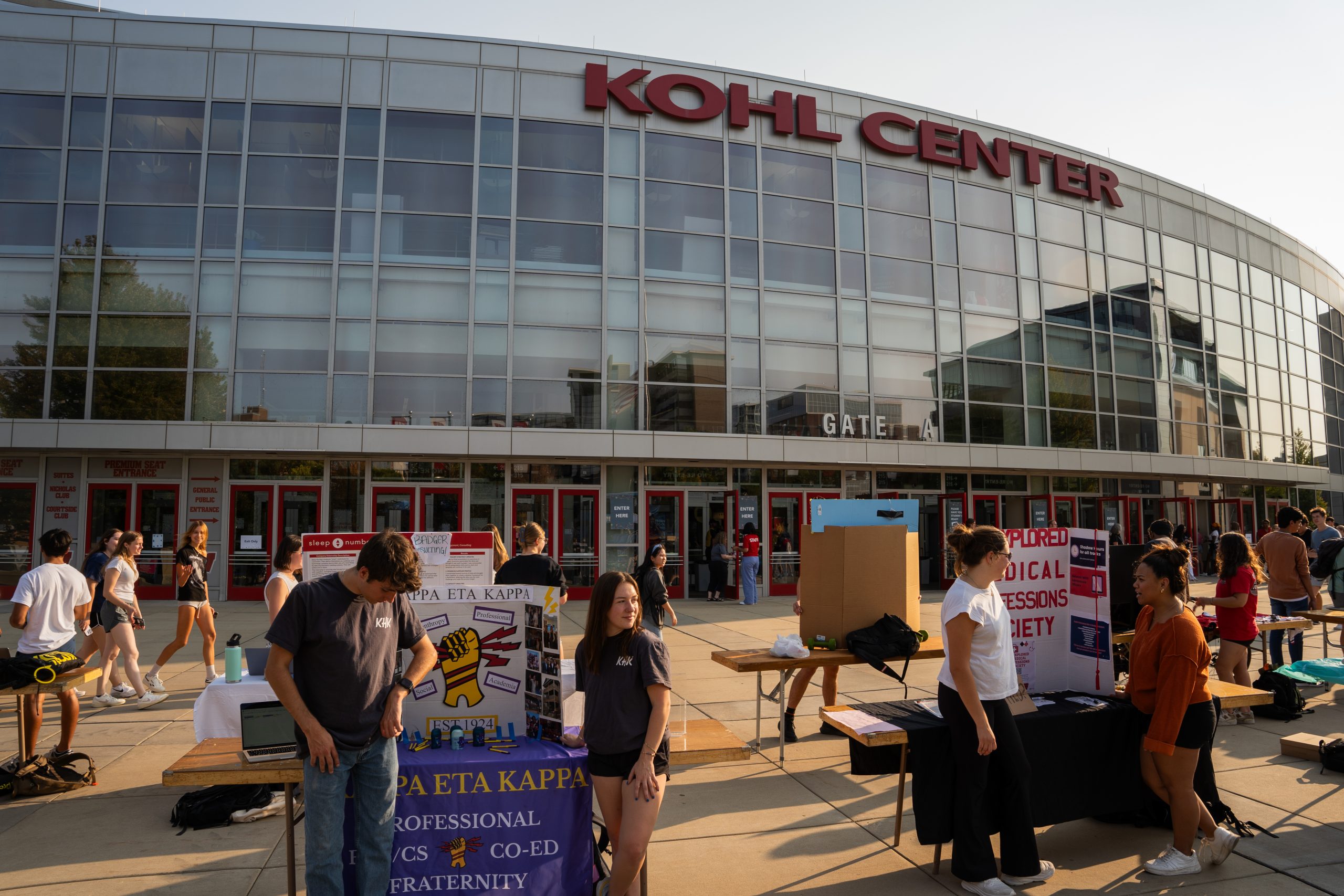Outside view of the Kohl Center at the Fall org fair. Students stand at table representing their organizations.