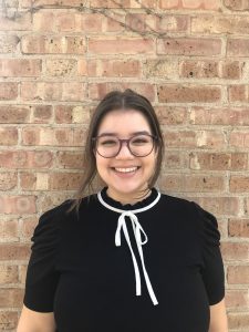 Woman smiling in front of brick wall